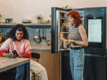 a person standing next to a person sitting at a table
