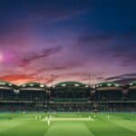 people watching game of cricket during sunset