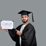 a person wearing a graduation cap and gown holding a sign