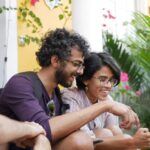 man in black polo shirt sitting beside woman in purple shirt
