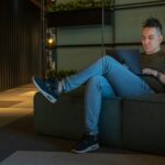 woman in gray long sleeve shirt and blue denim jeans sitting on gray couch