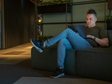 woman in gray long sleeve shirt and blue denim jeans sitting on gray couch