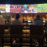 a group of people sitting at a bar watching tv