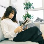 woman in white long-sleeved shirt and black skirt sitting on sofa
