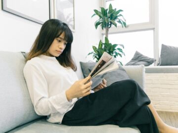 woman in white long-sleeved shirt and black skirt sitting on sofa