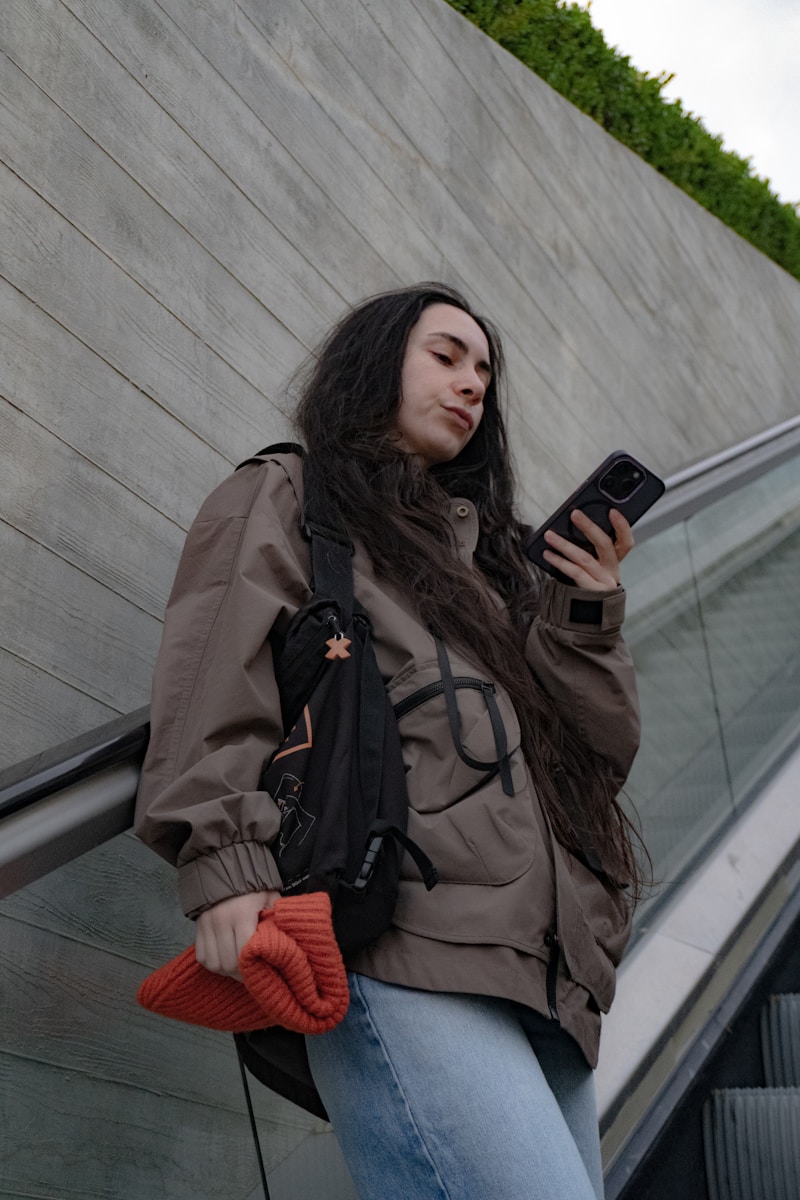 A woman checks her phone on an escalator.
