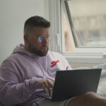 man in pink hoodie using macbook