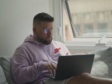 man in pink hoodie using macbook