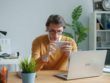 Man playing game on smartphone at desk
