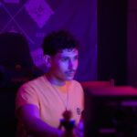 Young man in an orange shirt with purple lighting.