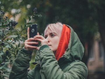 woman wearing green hooded jacket holding iPhone