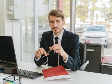 Business professional sitting at a desk with documents in an office environment.