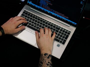 a man is typing on a laptop computer