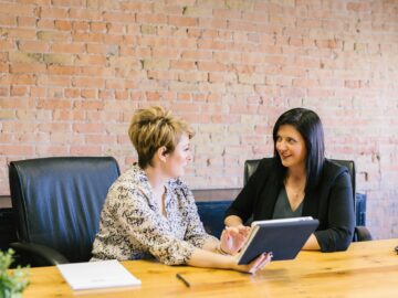 two women sitting on leather chairs in front of table