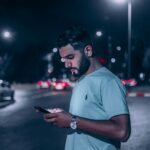 man in white polo shirt holding smartphone
