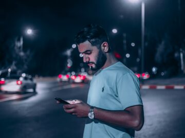 man in white polo shirt holding smartphone