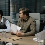 Three male colleagues engage in a business meeting discussing documents around a table.