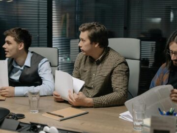 Three male colleagues engage in a business meeting discussing documents around a table.