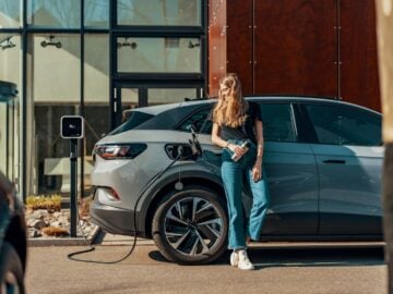 a woman standing next to a blue car