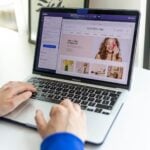 Hands typing on a laptop with an e-commerce website open, showcasing online shopping.