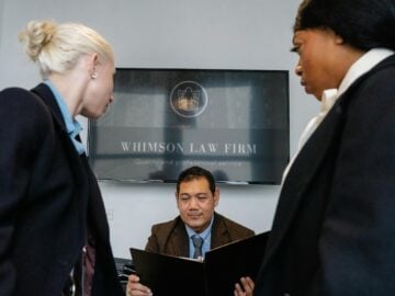 Diverse colleagues gathering in conference hall of law firm and discussing details of contract while working together