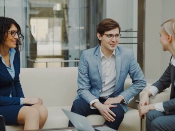 Three business people in a meeting on a couch.