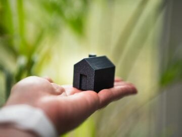 A person holding a small house in their hand