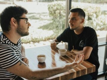two men having conversation on table