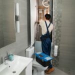 A plumber repairs plumbing in a bathroom.