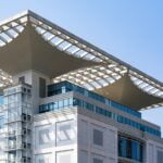 Modern building with glass facade and unique roof design.