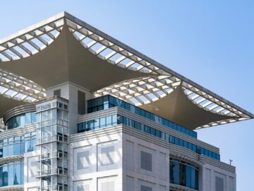 Modern building with glass facade and unique roof design.