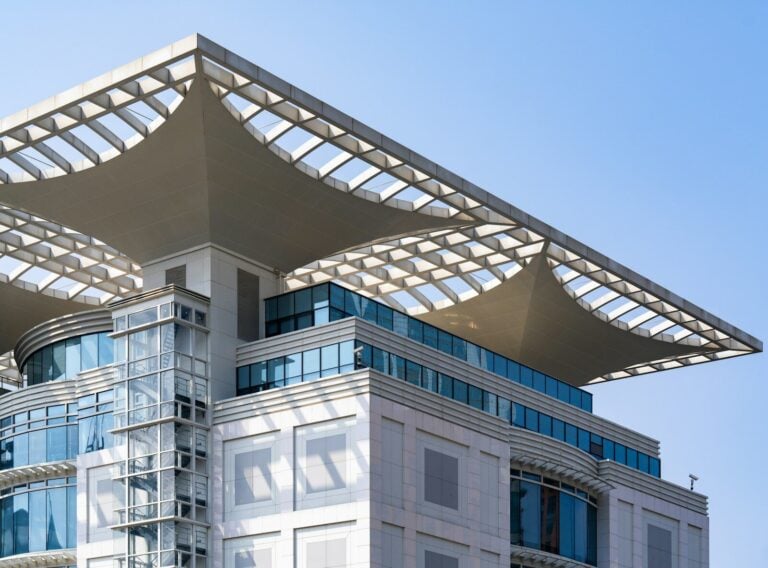 Modern building with glass facade and unique roof design.