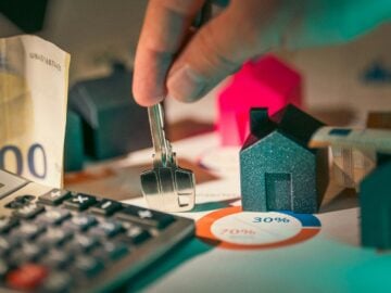 hand holding key over house models
