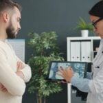 Doctor shows patient medical scan on tablet.