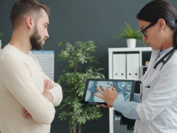 Doctor shows patient medical scan on tablet.