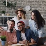a group of people standing around a table with a laptop