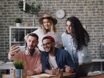 a group of people standing around a table with a laptop