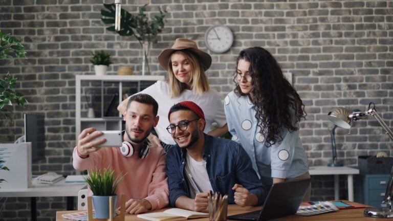 a group of people standing around a table with a laptop