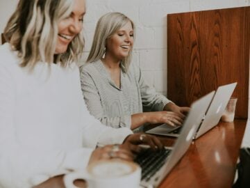 two women using laptops