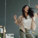 A woman joyfully dancing with arms raised.