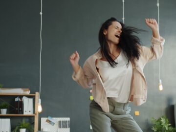 A woman joyfully dancing with arms raised.