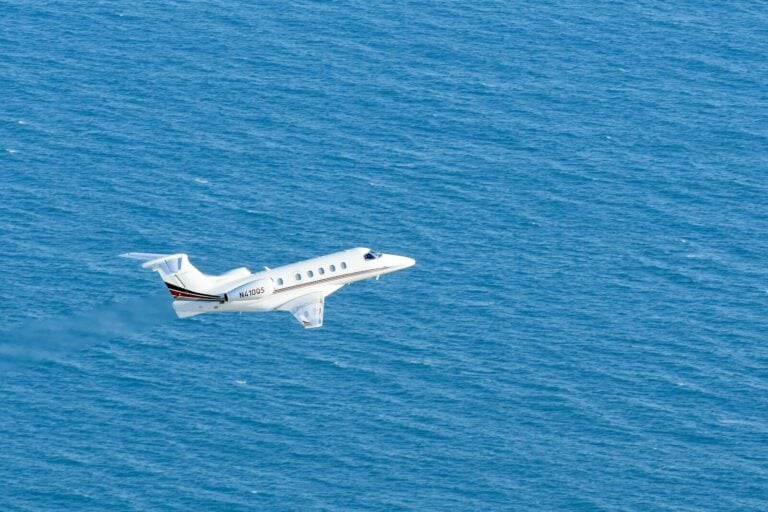 a small white plane flying over a large body of water