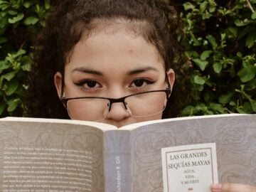 A young girl wearing glasses reading a book
